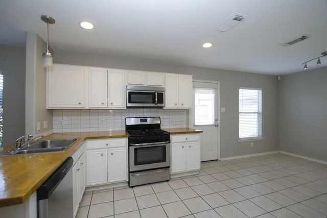 a kitchen with a sink a stove top oven and cabinets