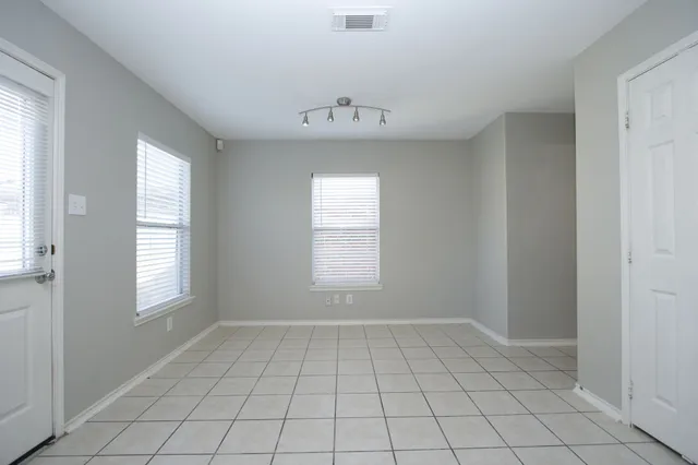 a kitchen with granite countertop a refrigerator and white cabinets