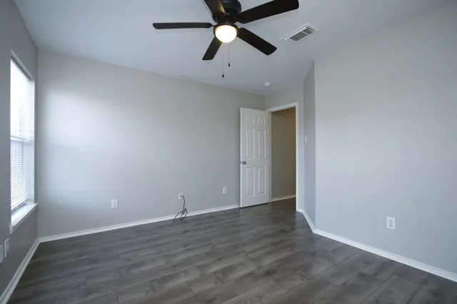 an empty room with wooden floor and windows