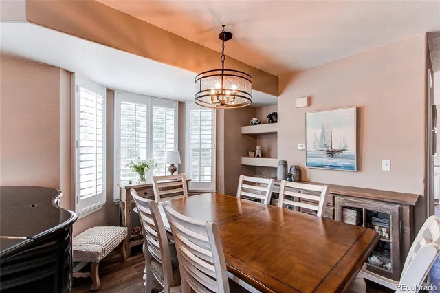 a dining room with wooden floor and large windows