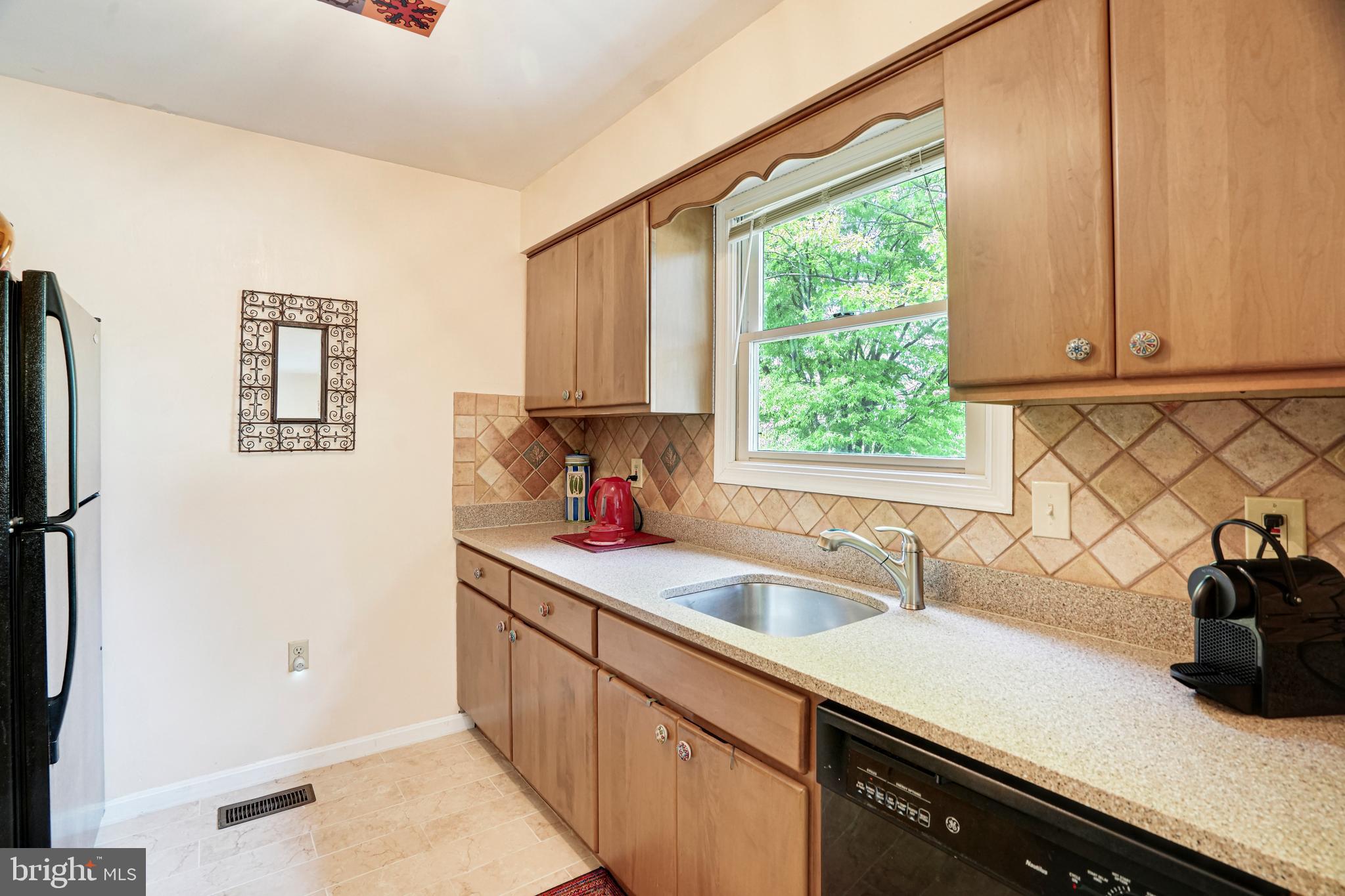 8872 Woodland Drive Silver Spring, MD 20910 - Photo 10 of 47 a kitchen with stainless steel appliances a sink a window and cabinets