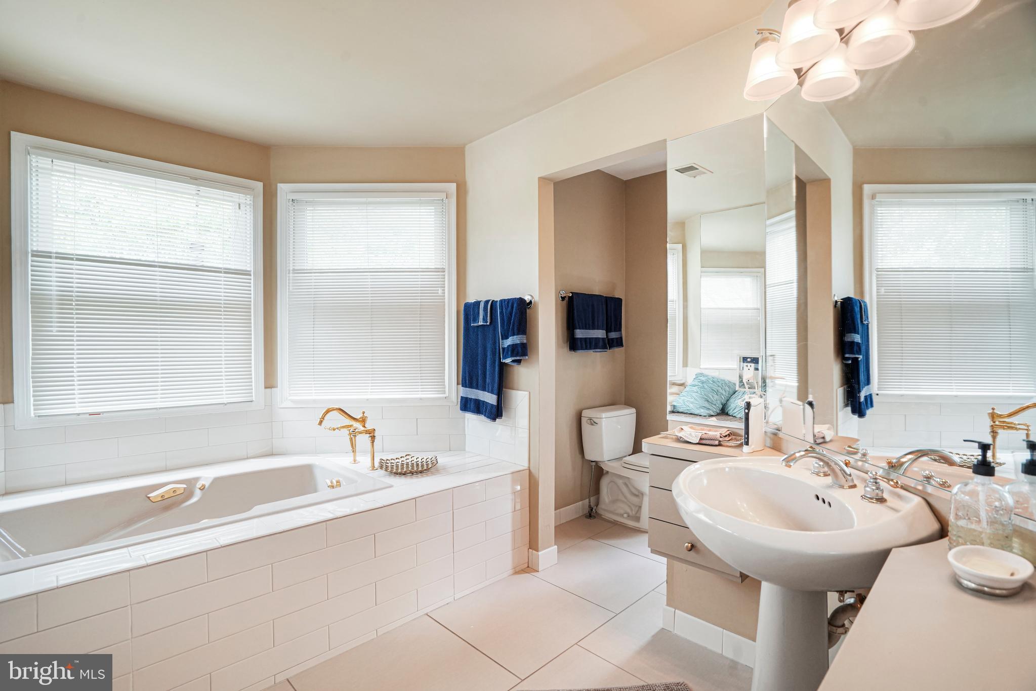 8872 Woodland Drive Silver Spring, MD 20910 - Photo 19 of 47 a bathroom with a sink mirror and a bathtub next to a window