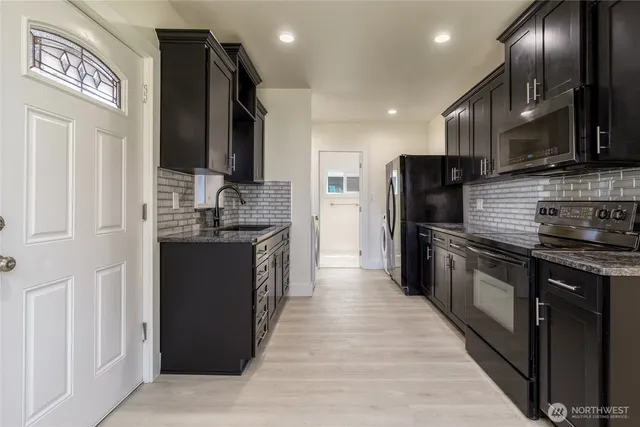 a kitchen with stainless steel appliances granite countertop a refrigerator a stove and a sink