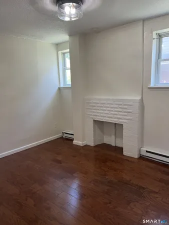 an empty room with wooden floor cabinet and windows