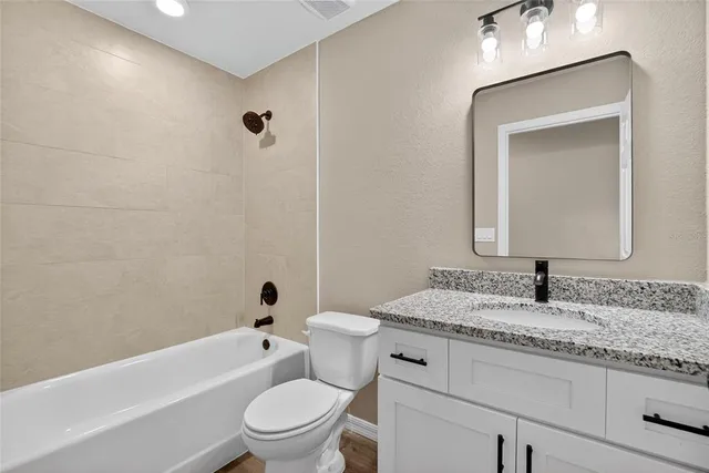 a bathroom with a granite countertop toilet a sink and a mirror