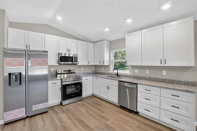 a kitchen with granite countertop white cabinets and stainless steel appliances