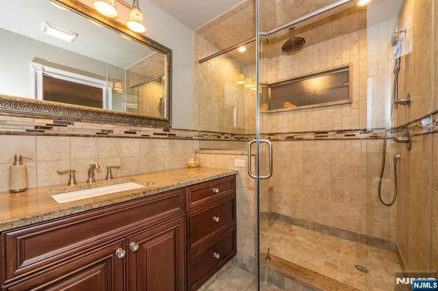 a bathroom with a granite countertop shower sink vanity and mirror