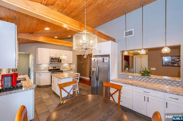 a kitchen with stainless steel appliances granite countertop a refrigerator a stove and white cabinets with wooden floors