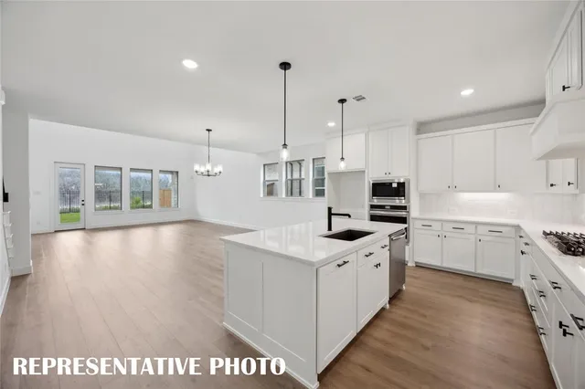 a kitchen with granite countertop a sink a stove and refrigerator
