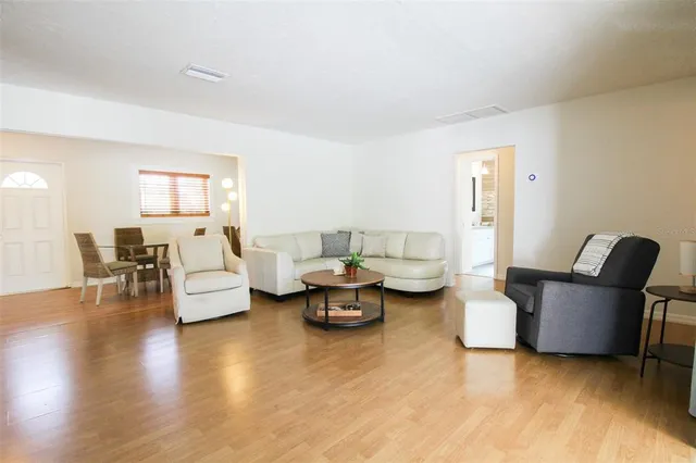 a living room with couches and a dining table with wooden floor