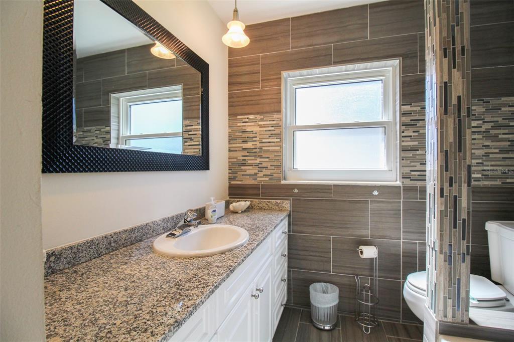 3223 Rowena Street Sarasota, FL 34231 - Photo 25 of 51 a bathroom with a granite countertop sink toilet a mirror and shower