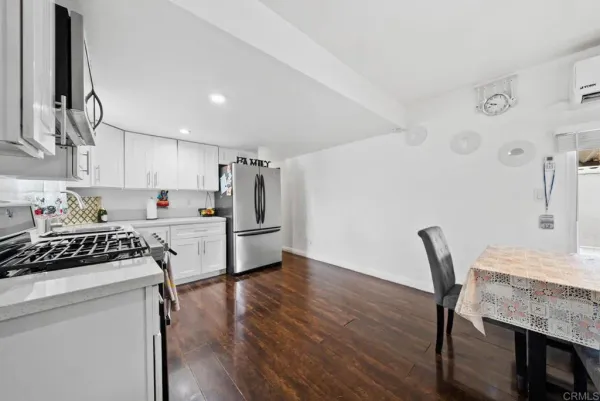 a kitchen with stainless steel appliances a refrigerator a stove a sink dishwasher and white cabinets with wooden floor