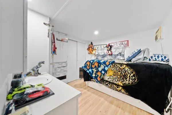 a bedroom with a bed a dresser and white comforter