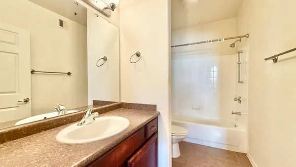 a bathroom with a granite countertop sink toilet mirror and shower