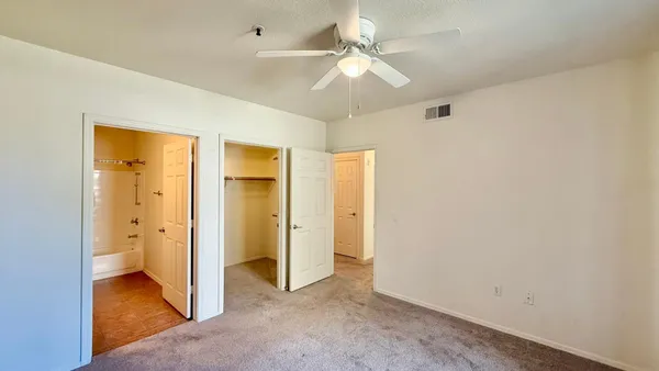 an empty room with a bathroom and a ceiling fan