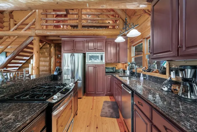 a kitchen with stainless steel appliances granite countertop a stove top oven a sink dishwasher and cabinets with wooden floor