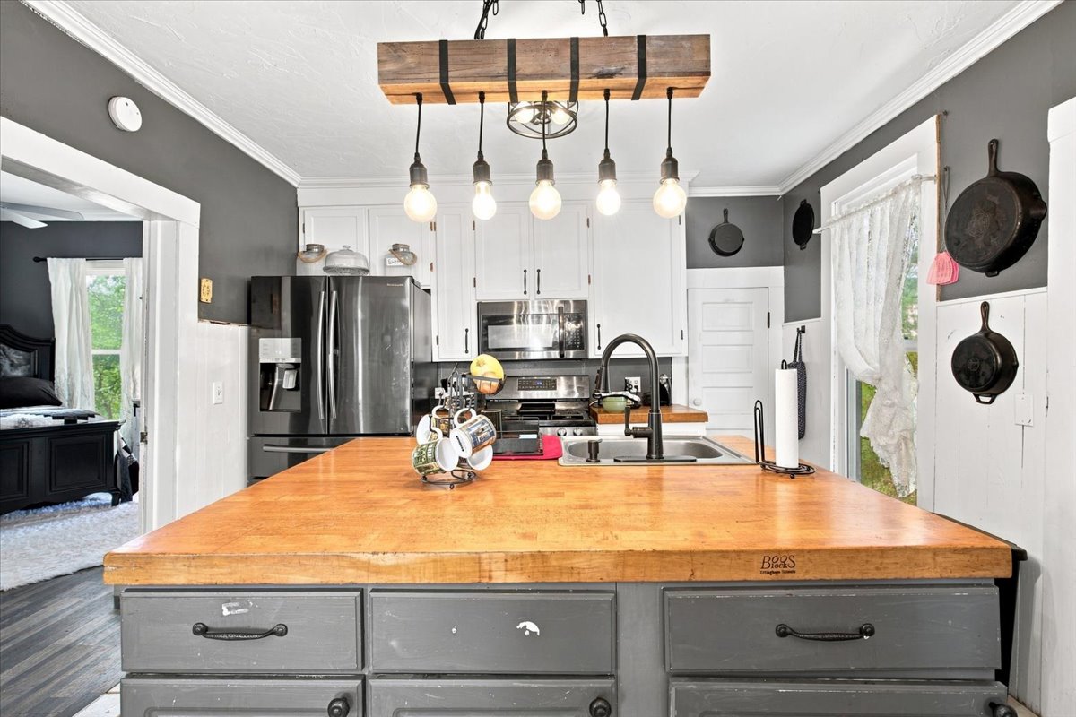 407 South 7 Springs Road Tishomingo, OK 73460 - Photo 10 of 45 Kitchen island with a wood-finish countertop, undermount sink, and dark hardware