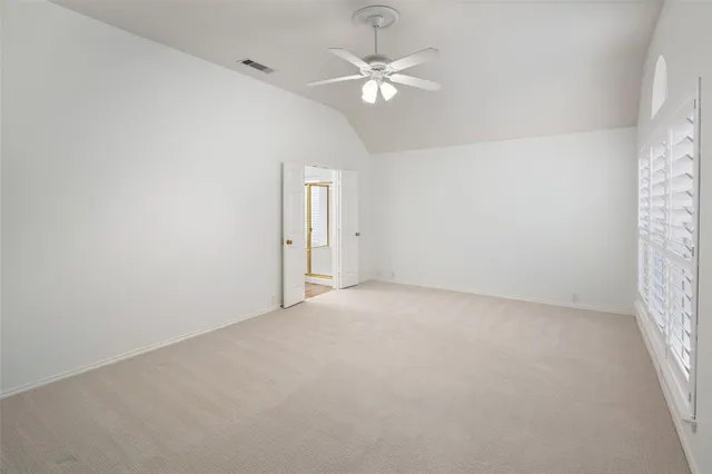 an empty room with windows and ceiling fan