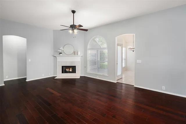 a view of an empty room with wooden floor fireplace and a window