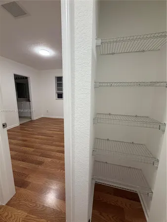 a view of an empty room with wooden floor and windows