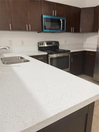 a kitchen with granite countertop a sink a stove top oven and wooden cabinets