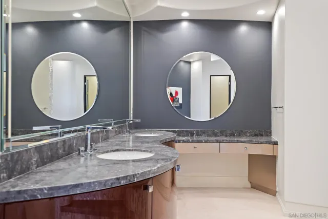 a bathroom with a granite countertop double vanity and a mirror