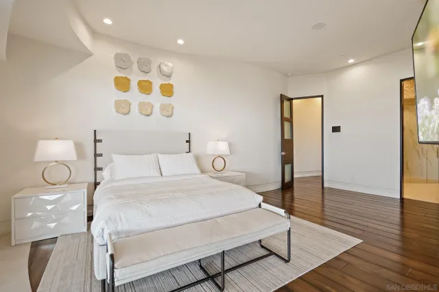 a bedroom with a bed a chandelier with bathroom and mirror