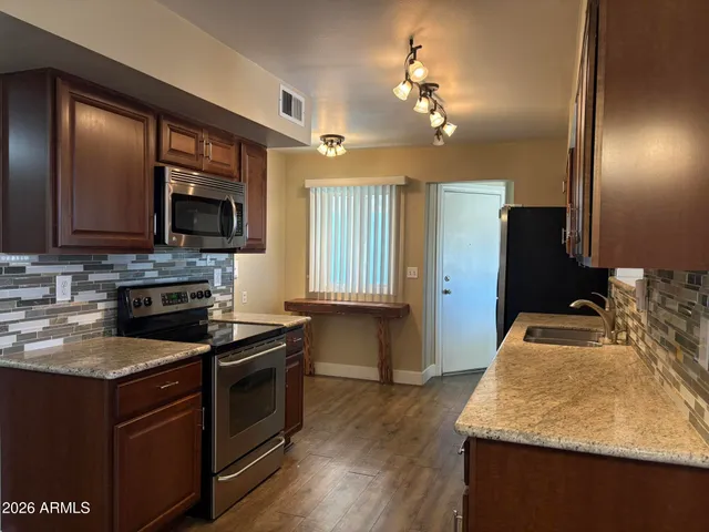 a kitchen with kitchen island granite countertop stainless steel appliances a stove sink microwave and refrigerator