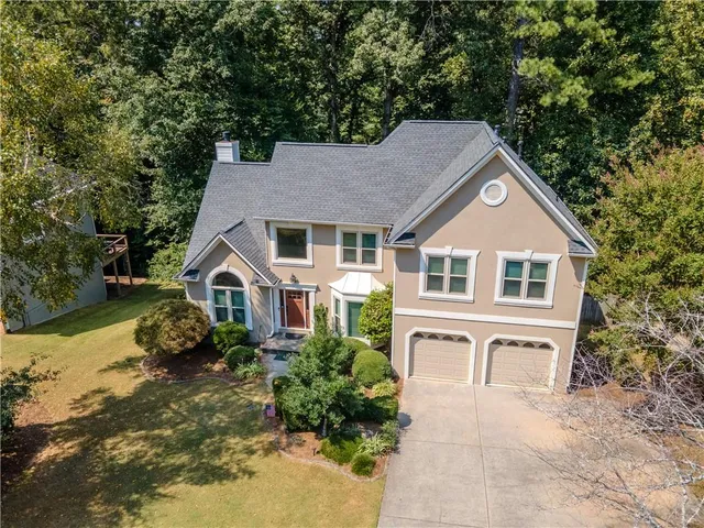 a front view of a house with a yard and trees