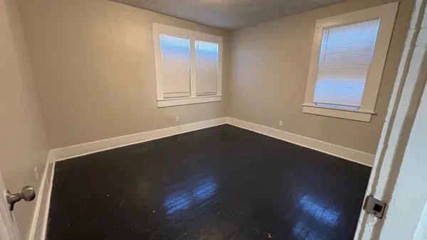 an empty room with wooden floor and windows