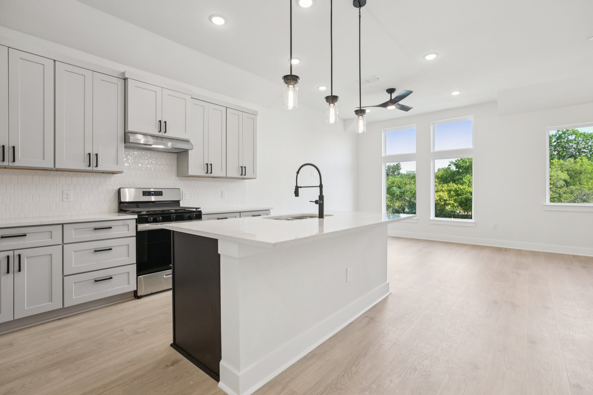 a kitchen with kitchen island granite countertop a stove a sink and a window