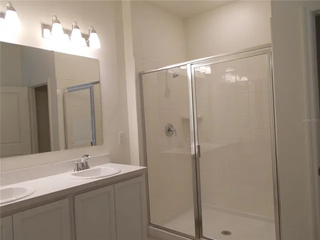 a bathroom with a double vanity sink mirror and shower