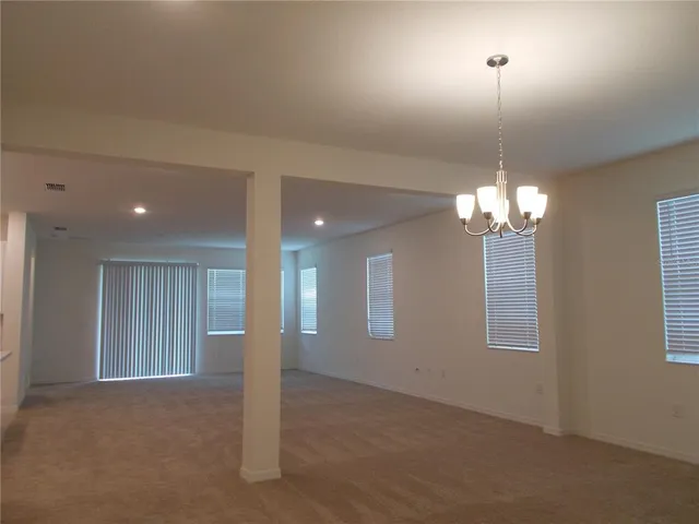 a view of a livingroom with a chandelier fan and windows