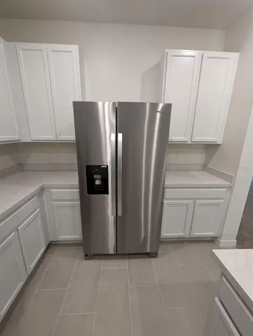 a view of a refrigerator in kitchen and cabinets