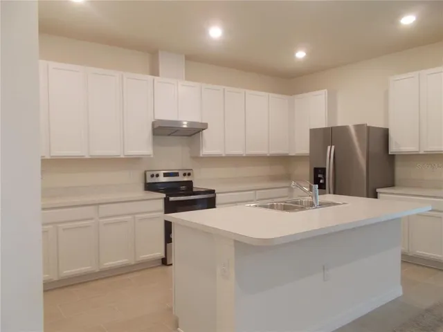 a kitchen with a refrigerator and a stove top oven