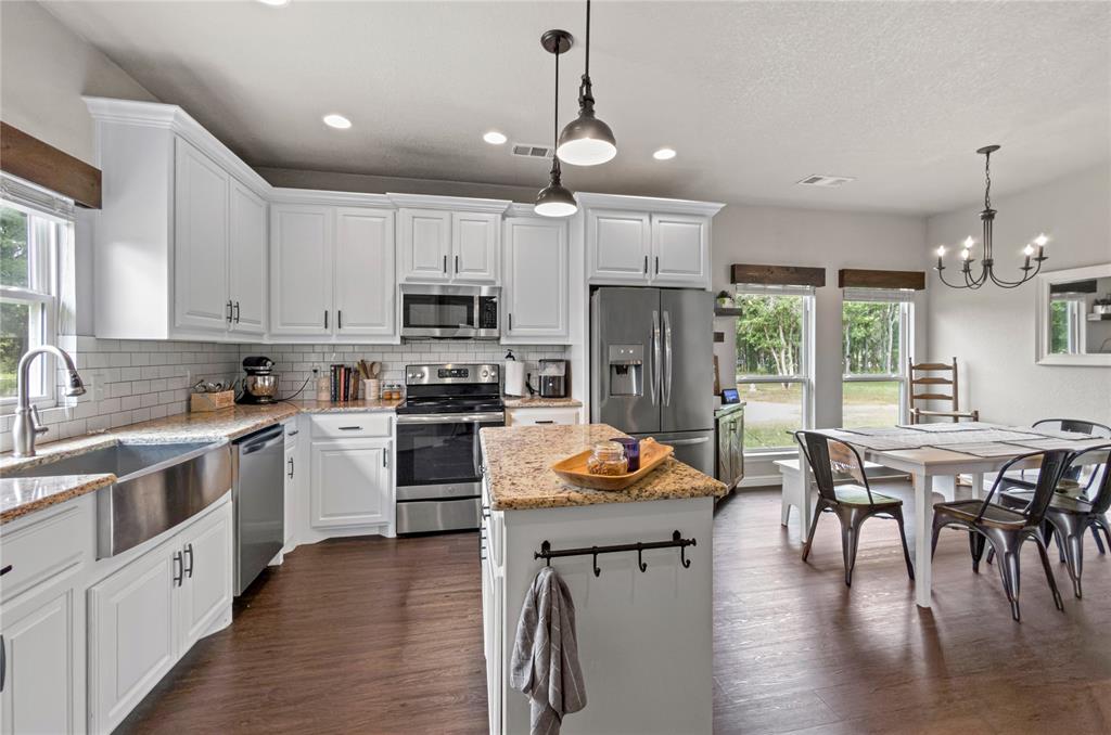 6093 Farm To Market Road 730 North Decatur, TX 76234 - Photo 9 of 28 a kitchen with stainless steel appliances granite countertop a stove top oven a sink dishwasher a dining table and chairs with wooden floor