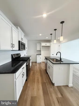 a kitchen with kitchen island a counter top space a sink stainless steel appliances and cabinets