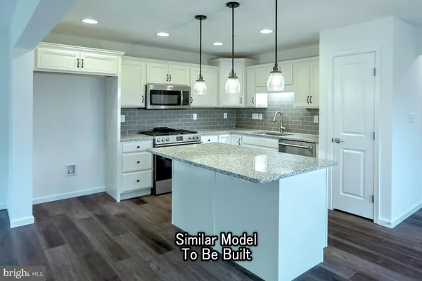 a kitchen with kitchen island a counter top space a sink stainless steel appliances and cabinets