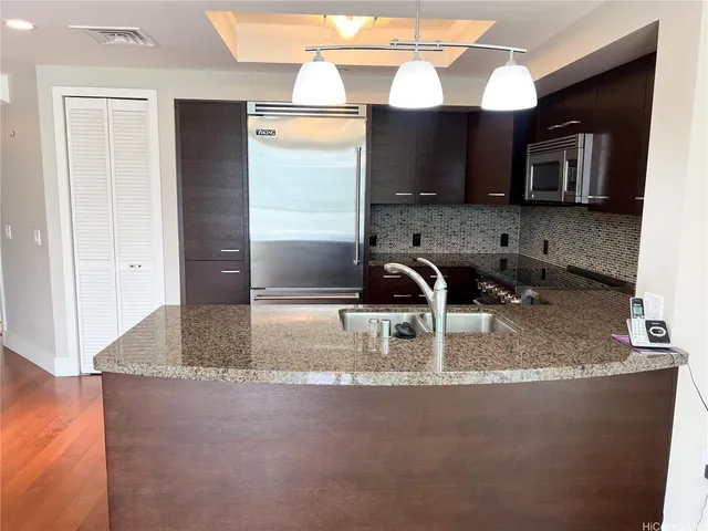 a kitchen with kitchen island granite countertop a sink a microwave and a refrigerator