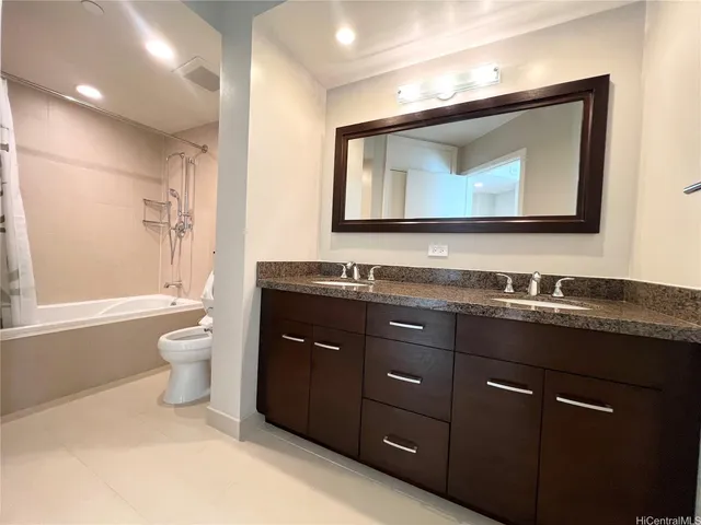 a bathroom with a granite countertop toilet a sink and a mirror