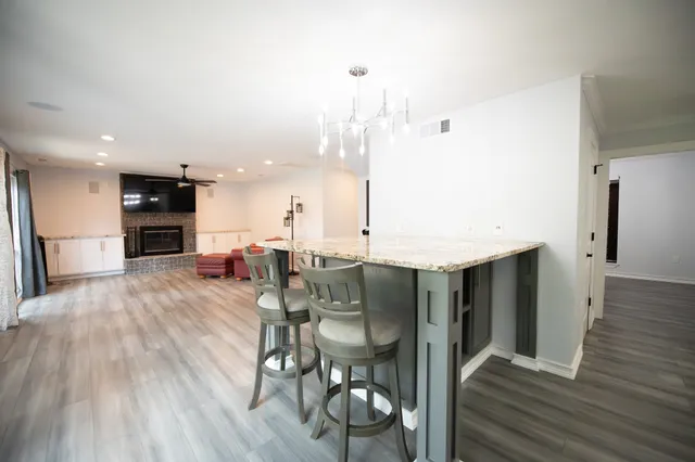 a dining hall with stainless steel appliances kitchen island granite countertop a table chairs and a refrigerator