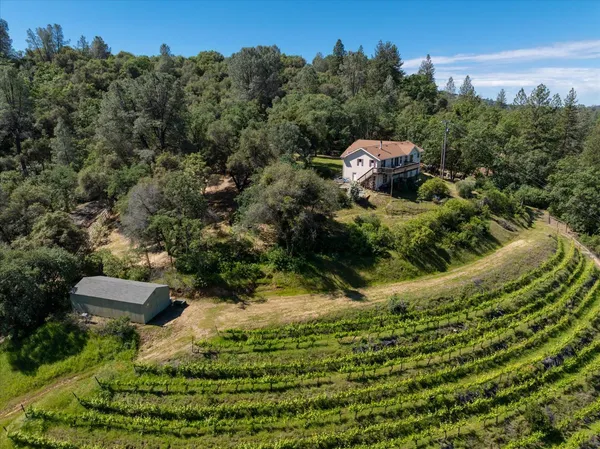 an aerial view of residential house with outdoor space and trees all around