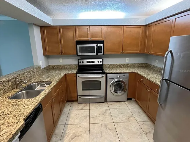 a kitchen with granite countertop a sink a stove top oven and refrigerator