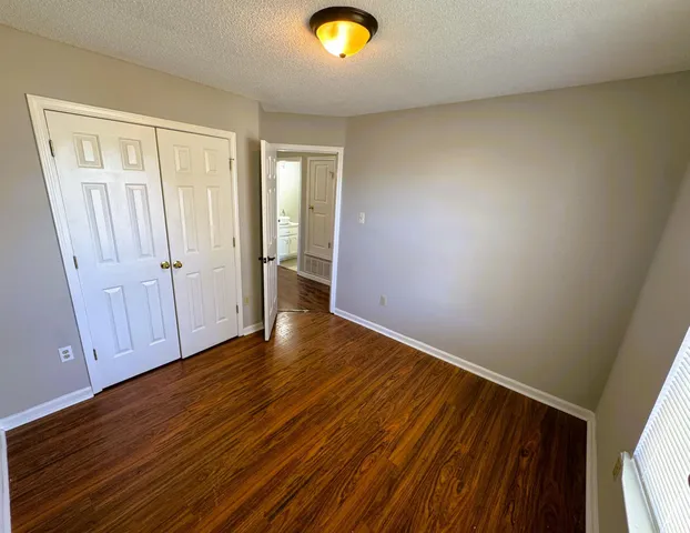 a view of an empty room with wooden floor and closet