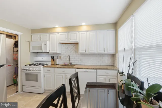 a kitchen with white cabinets stainless steel appliances and a window