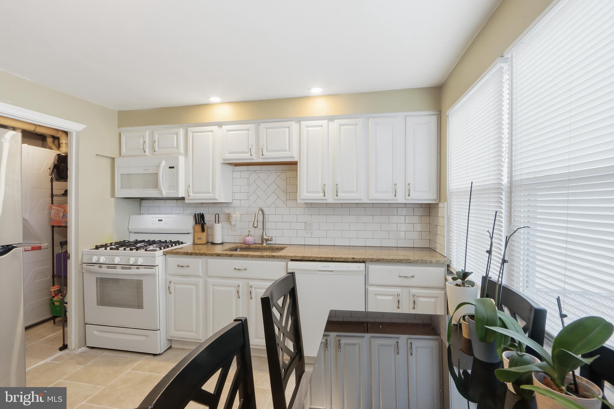 4432 Annapolis Road Baltimore, MD 21227 - Photo 17 of 31 a kitchen with white cabinets stainless steel appliances and a window