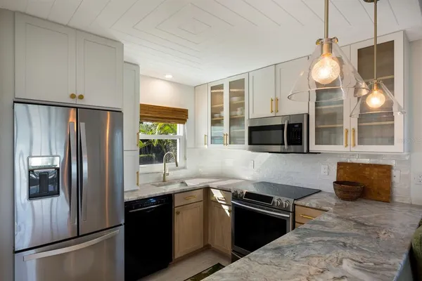 a kitchen with stainless steel appliances granite countertop a refrigerator a sink a stove and a refrigerator with wooden floor