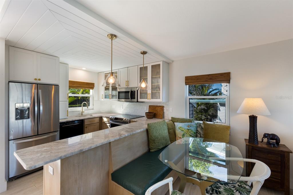 5850 Gasparilla Road, Unit M7 Boca Grande, FL 33921 - Photo 9 of 54 a kitchen with stainless steel appliances granite countertop a sink a stove a refrigerator white cabinets a dining table and chairs