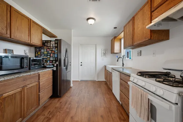 a kitchen with stainless steel appliances granite countertop wooden cabinets a stove a sink and a microwave