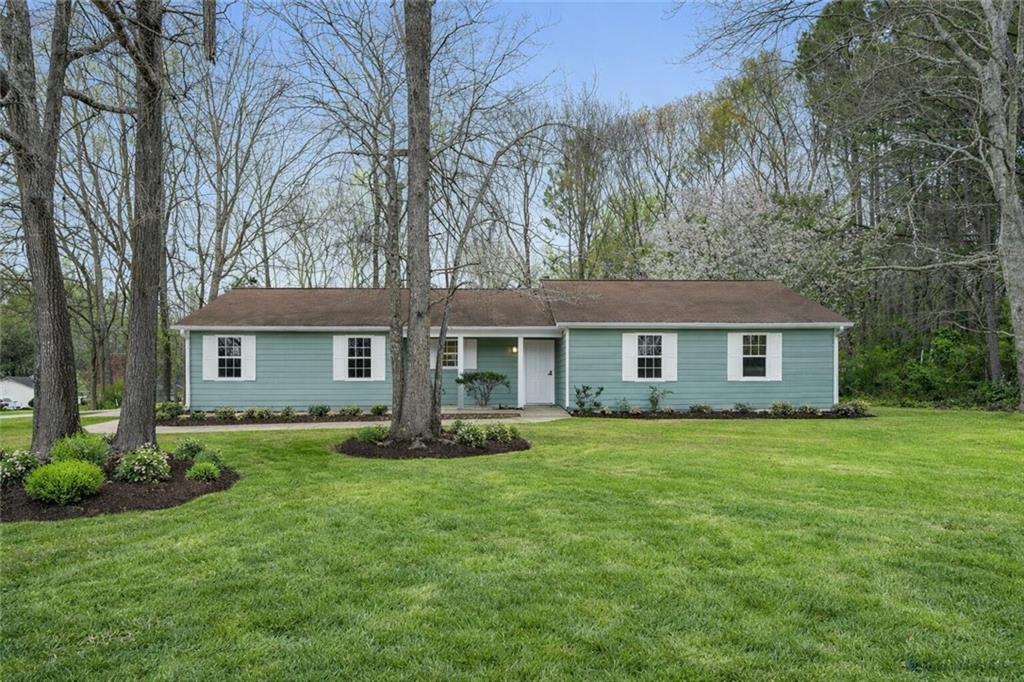 a front view of a house with a garden and trees